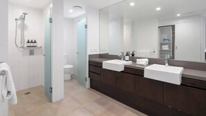 Une salle de bain moderne avec deux lavabos, un grand miroir et un espace douche.