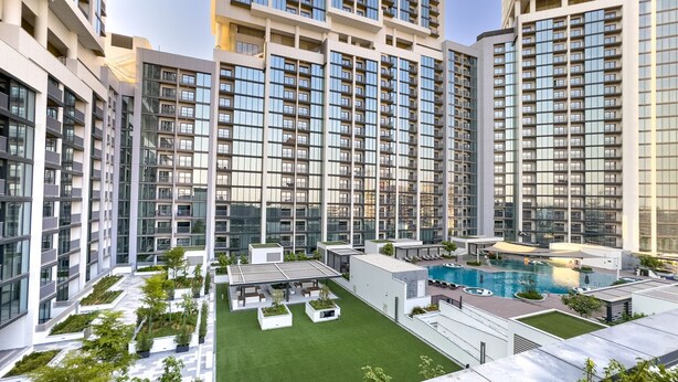 A modern high-rise residential building with multiple balconies, a rooftop pool, and landscaped terraces. - Skyline Views 2BR, Steps from a Park, Minutes Drive to Meydan Golf Club (Dubai)