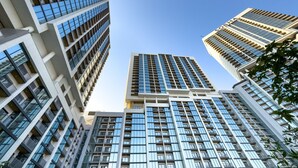 A high-rise building with a modern architectural design, featuring multiple floors with large windows and a prominent central entrance. - Skyline Views 2BR, Steps from a Park, Minutes Drive to Meydan Golf Club (Dubai)