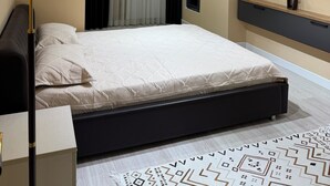 A modern bedroom with a bed, a bedside lamp, a wall-mounted air conditioner, and a built-in TV. - Serenity   (Dushanbe)