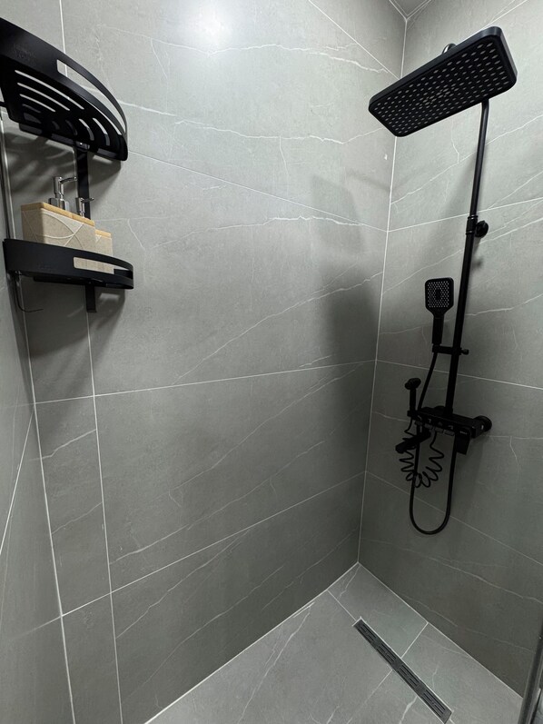 Une douche moderne dotée d’un pommeau de douche à main et d’un robinet mural.