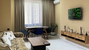 A modern living room with a sofa, coffee table, and a dining area with chairs and a table. - Serenity   (Dushanbe)