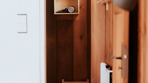 Une armoire en bois avec une étagère, un petit tabouret en bois et une lampe.