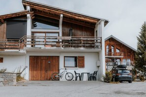 Un bâtiment à deux étages doté d’un balcon en bois, avec un vélo et une voiture garés devant.