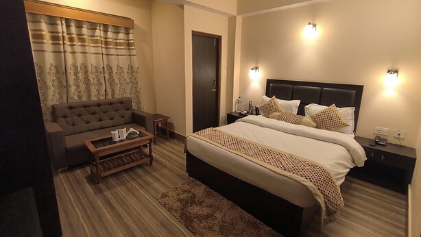 A bedroom with a bed, a sofa, a coffee table, a nightstand, and a ceiling fan.