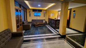 A modern lobby with a sofa, a reception desk, and a television screen.