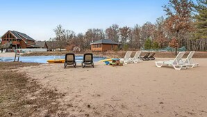 A beach with lounge chairs and a pool.
