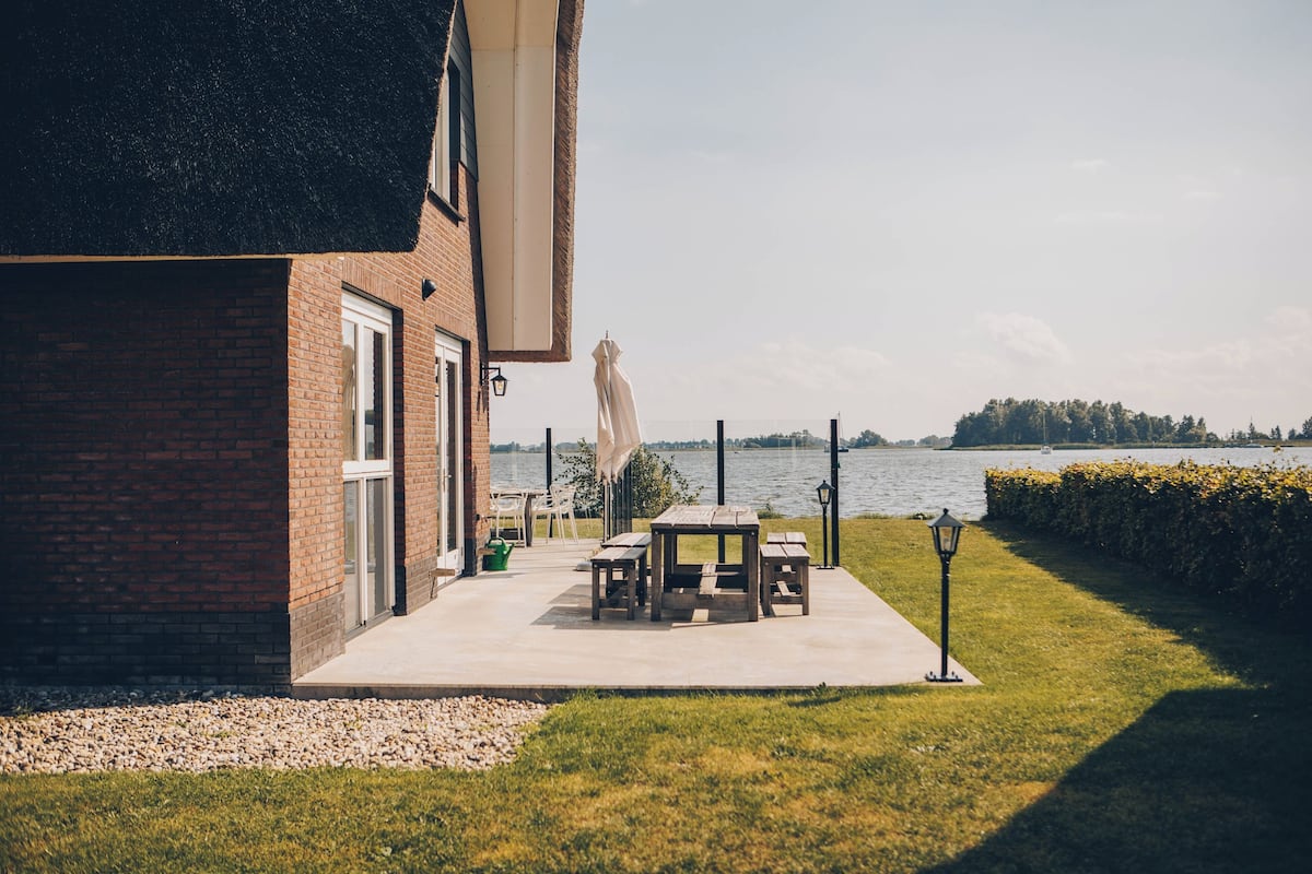 A patio with a table and chairs, a lamp, and a view of a lake.