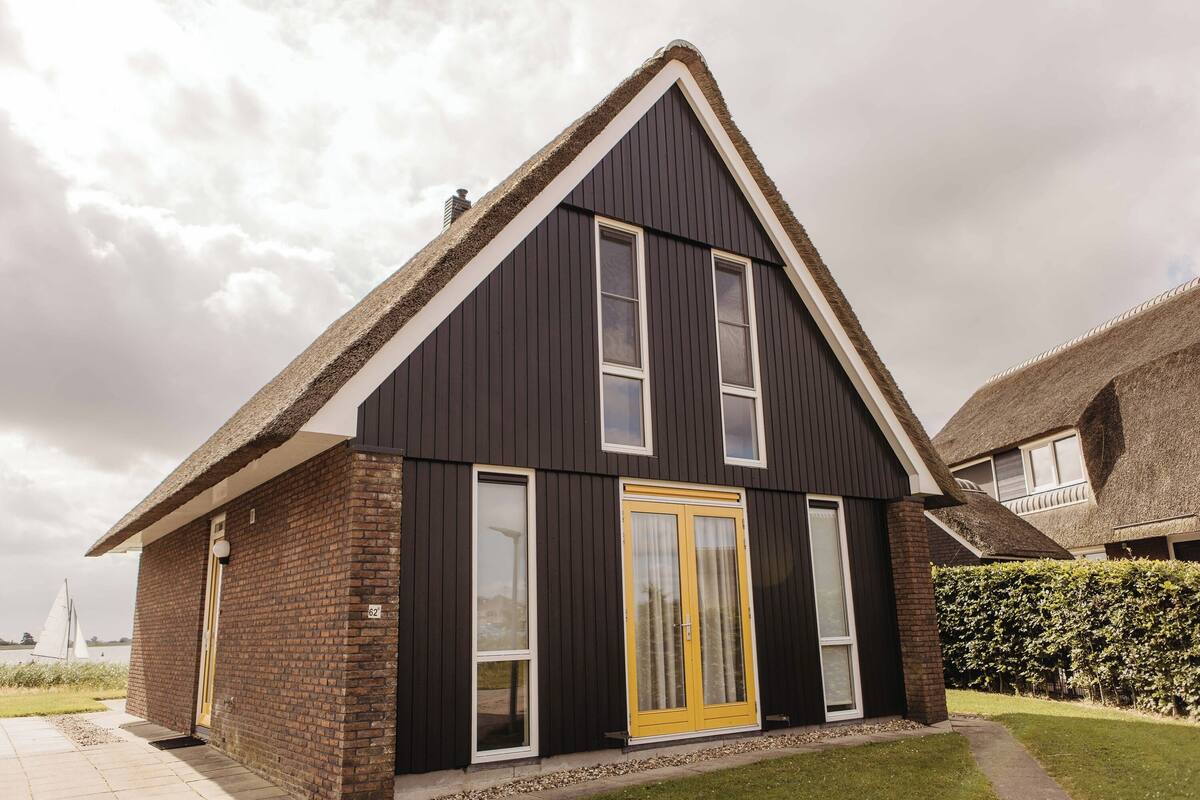A modern house with a dark facade, a yellow door, and a brick exterior.