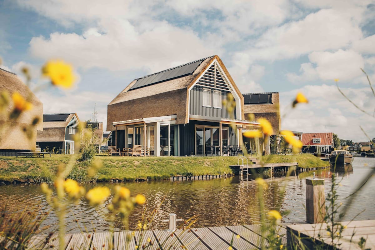 A riverside building with a modern design, featuring large windows and a covered outdoor area.