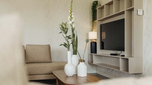 Un salon moderne avec un canapé beige, une table basse en bois et trois vases blancs ornés de plantes.