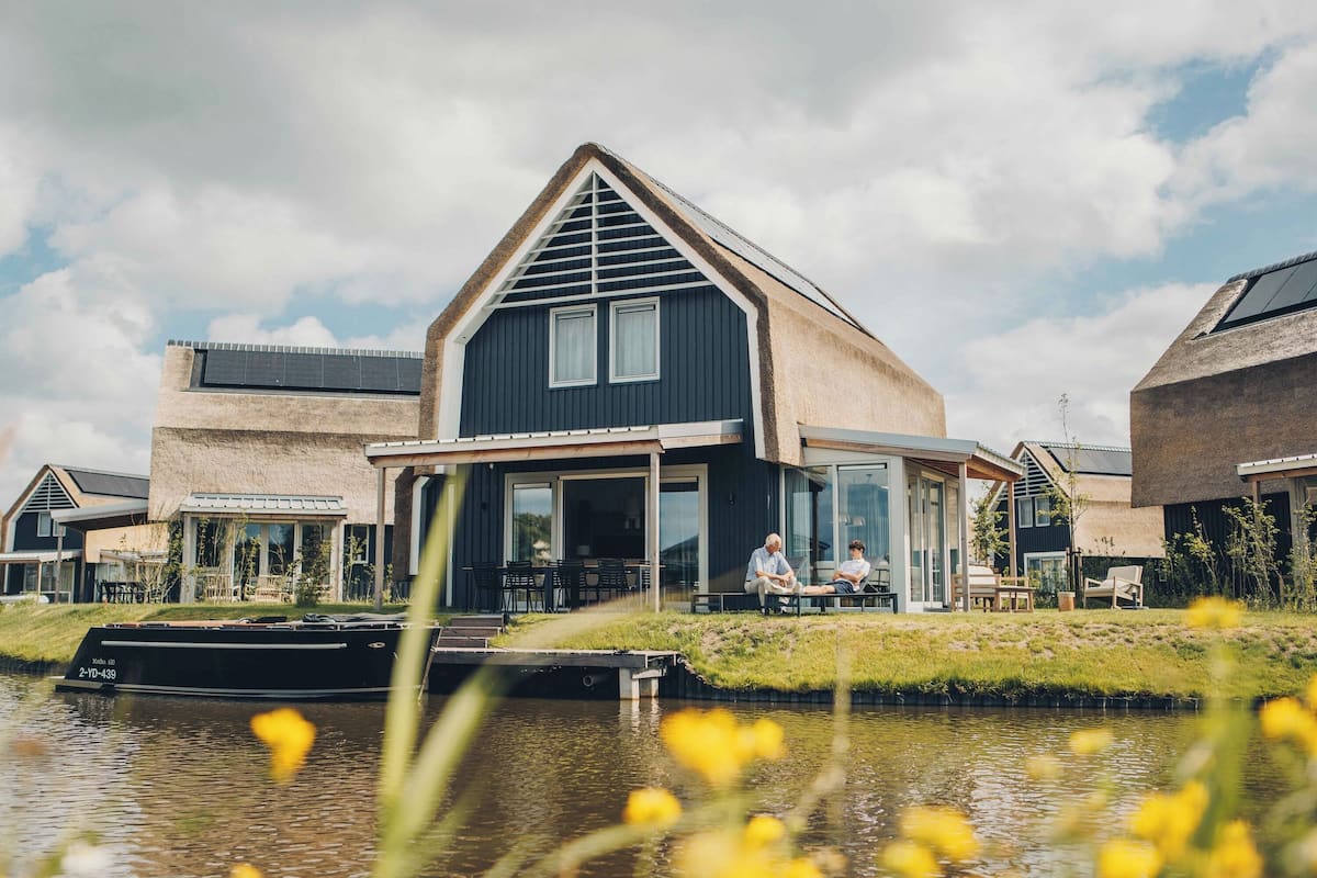 A modern house with a large glass door, a dock, and a canal in front.