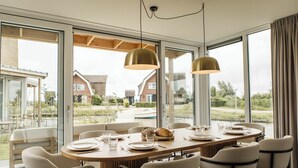 Un espace repas comprenant une grande table, des chaises et des luminaires suspendus.