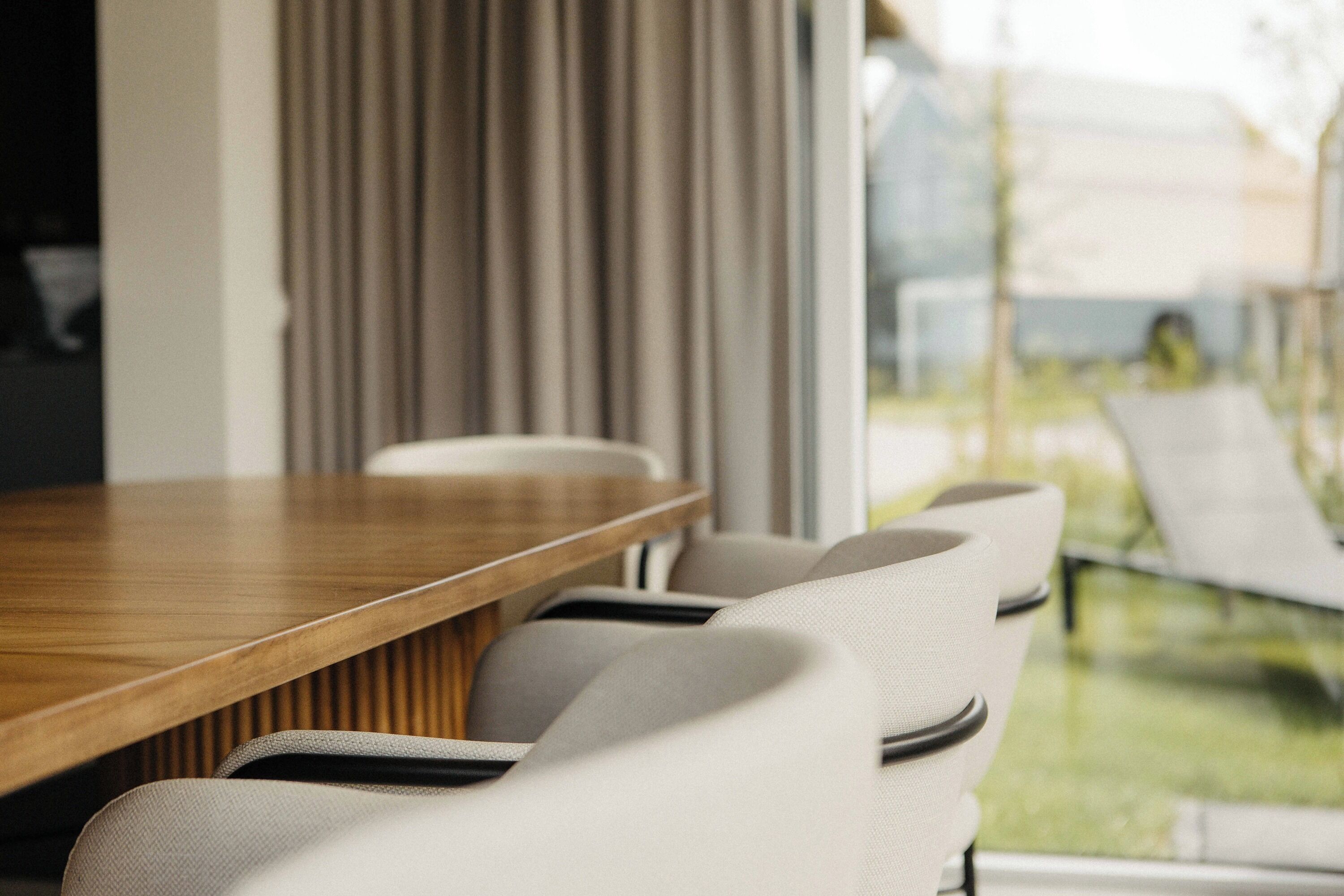 A modern dining area with a wooden table and upholstered chairs.