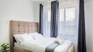 A neatly made bed with a tufted headboard, a white pillow, and a folded blanket.