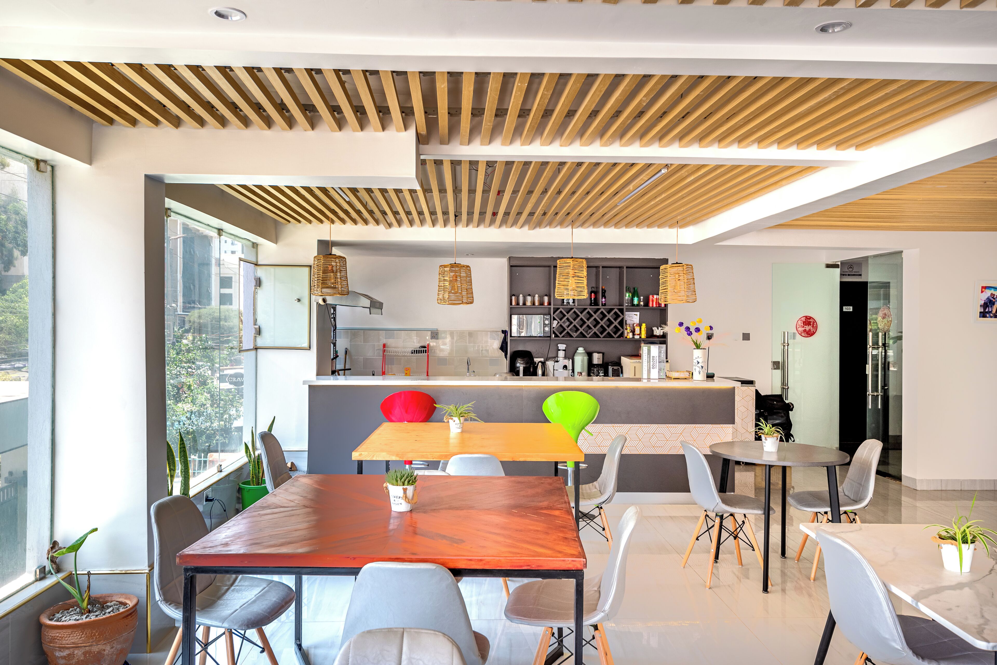 A modern dining area with a wooden ceiling, a bar, and a view of the city.