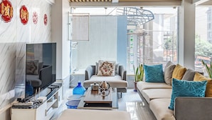 A modern living room with a sofa, ottoman, and a TV.