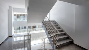 A modern interior with a staircase leading to an upper level, large windows, and a polished floor.
