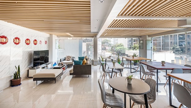 A modern hotel lobby with a sofa, TV, and dining area.
