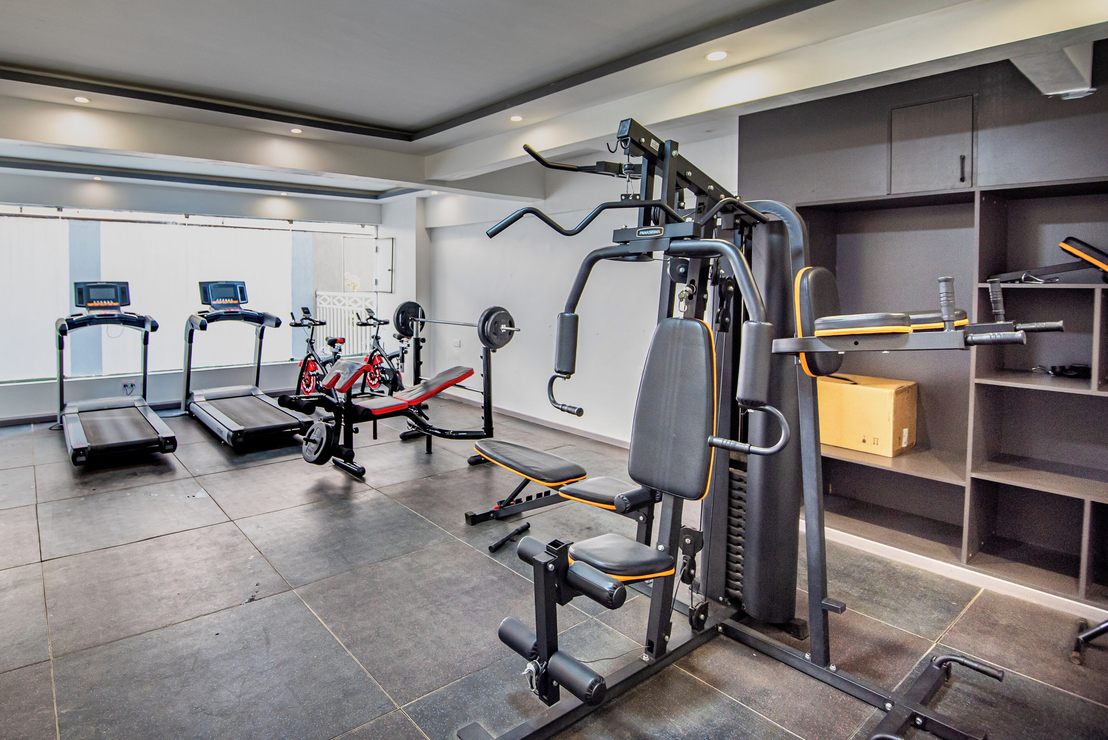 Una palestra con tapis roulant, macchinari per pesi e una panca per il sollevamento pesi.