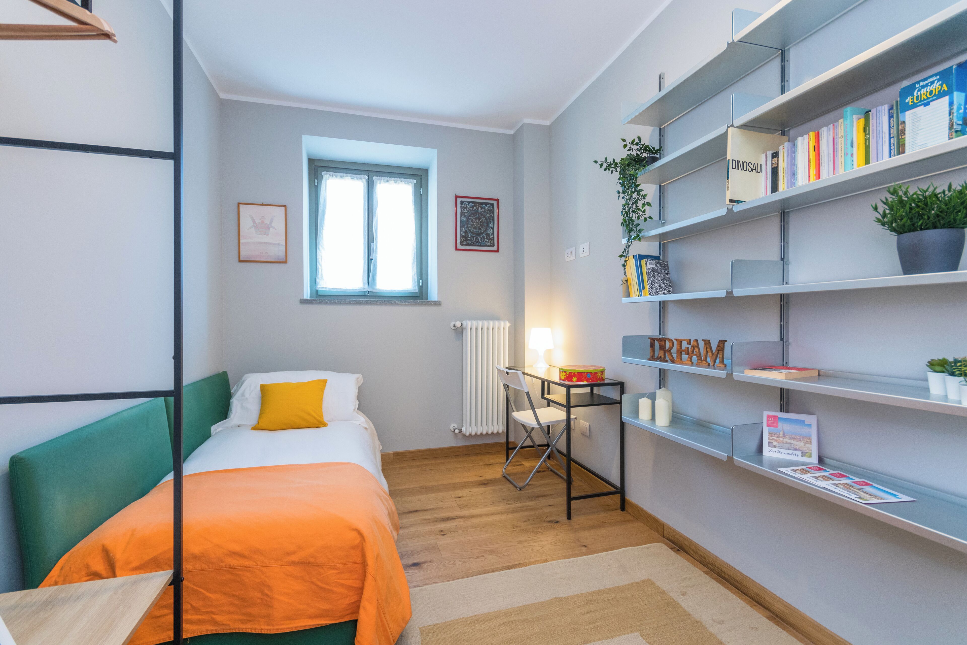 A compact room with a bed, a desk, and a bookshelf.