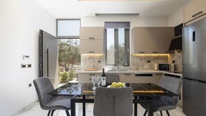 Una cucina moderna con zona pranzo, caratterizzata da un'ampia finestra, elettrodomestici integrati e pavimento in marmo.