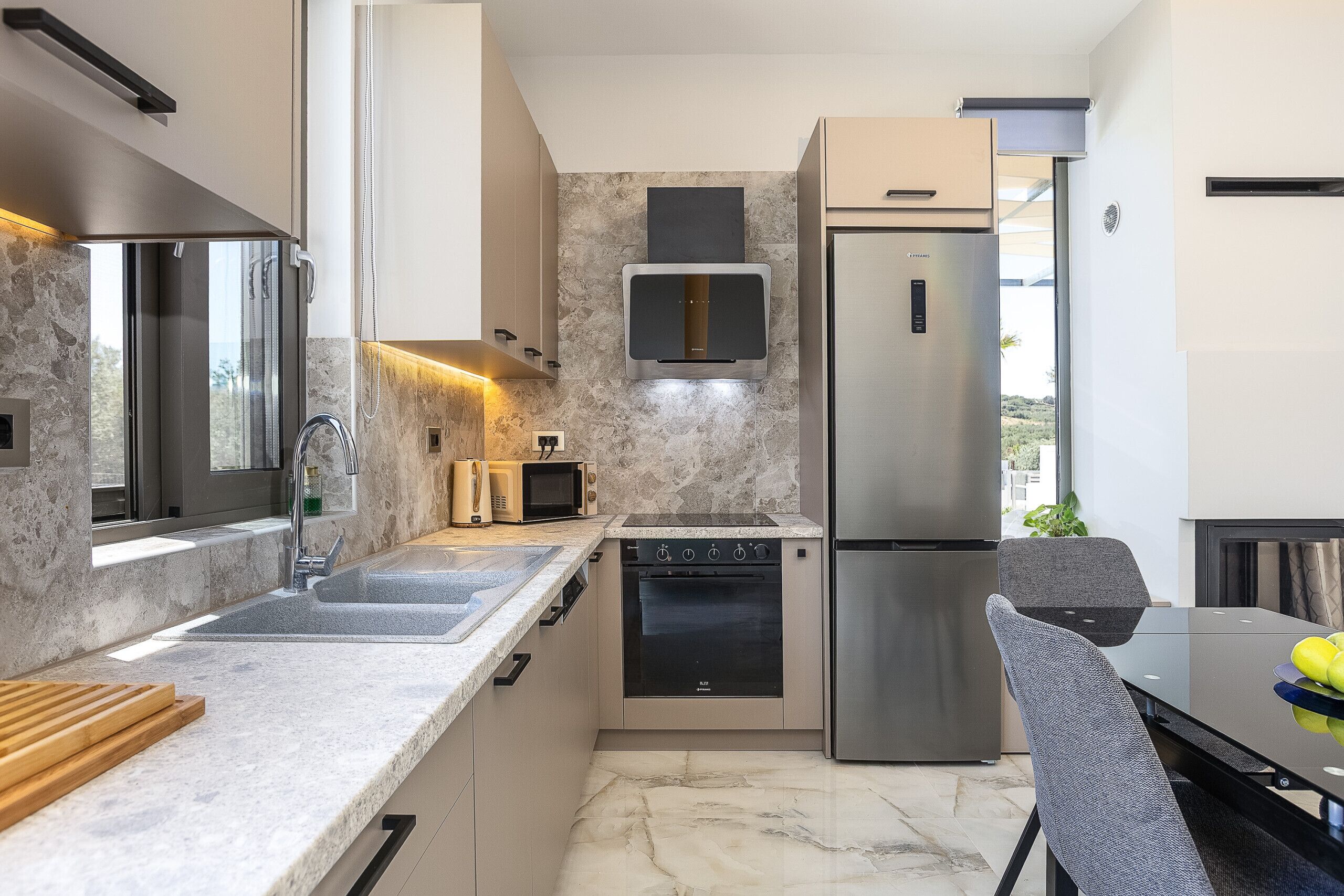 Una cocina moderna con horno integrado, microondas y refrigerador de acero inoxidable.