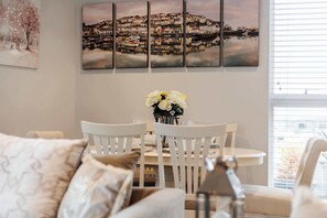 A dining area with a round table, white chairs, and a vase of flowers. - Harbour Edge - With Front-Line Harbour Views (Poole)