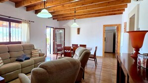 A living room with a sofa, chairs, a dining table, and a kitchen area.