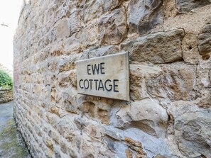 A wooden sign on a stone wall that reads "EWE COTTAGE." - Ewe Cottage (Ripon)