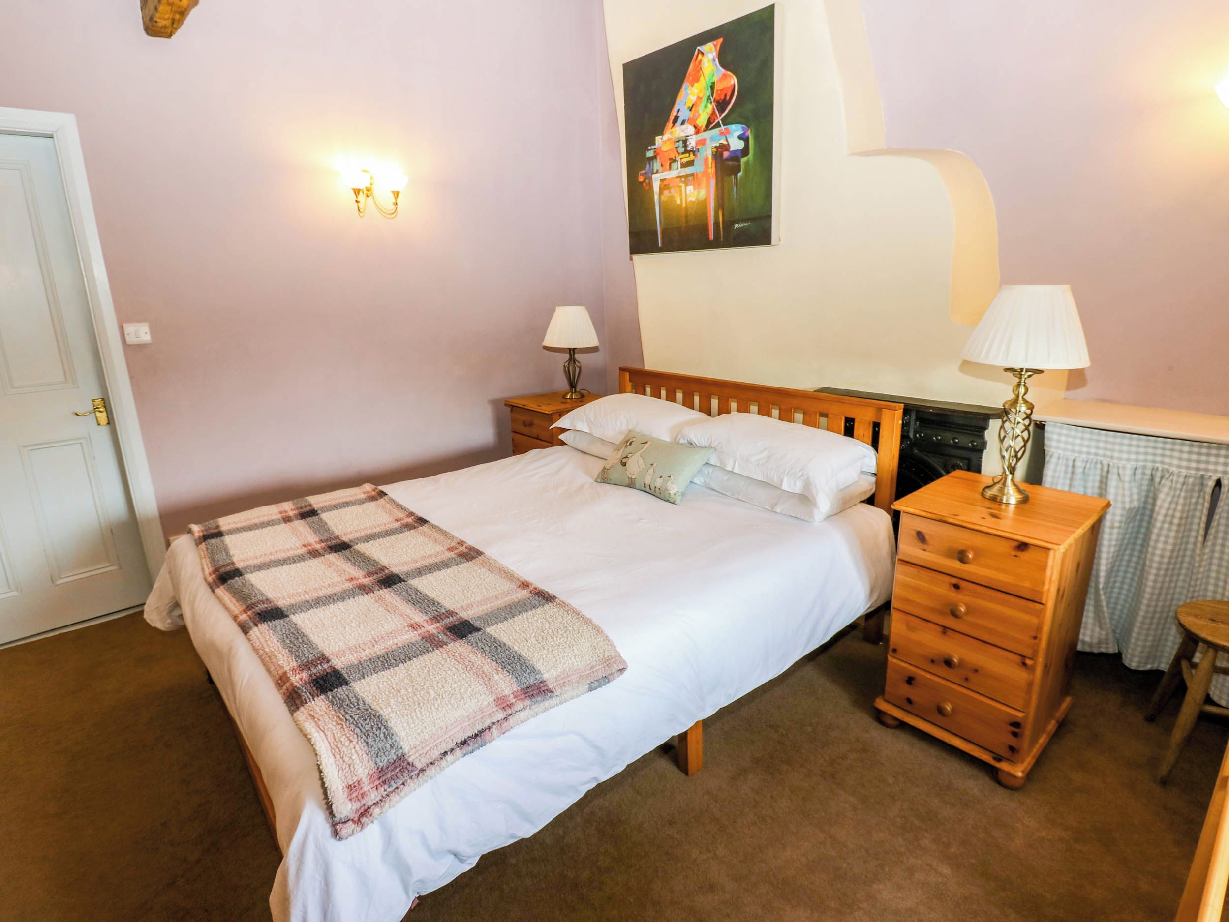 A bedroom with a bed, bedside tables, a lamp, a dresser, and a painting on the wall.