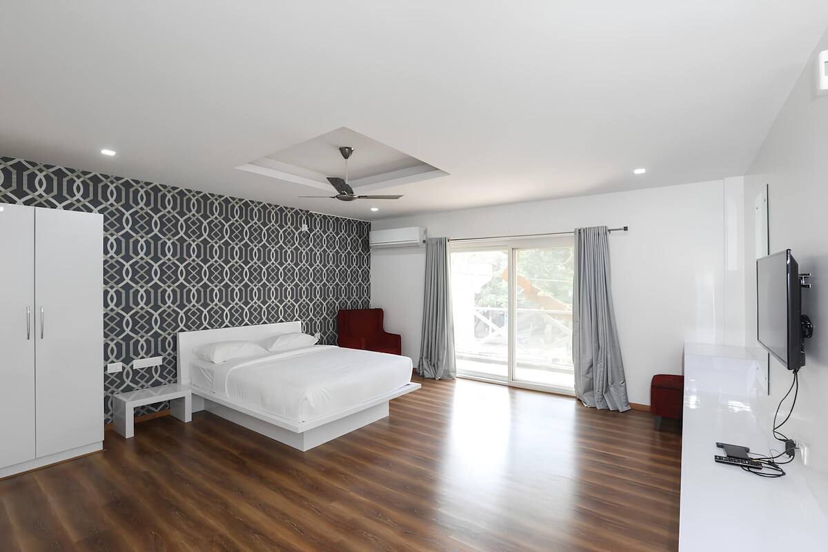 Une chambre moderne équipée d’un lit, d’une armoire, d’un ventilateur de plafond et d’un téléviseur.