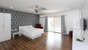Ein modernes Schlafzimmer mit Bett, Kleiderschrank, Deckenventilator und Fernseher.