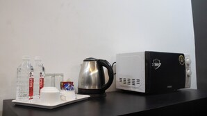 Eine Küchenzeile mit einer Kaffeemaschine, zwei Wasserflaschen, einer Tasse und einer Mikrowelle.
