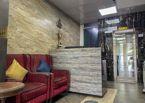 A reception area with a reception desk, a sofa with striped upholstery, and a marble wall.