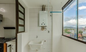 Ein Badezimmer mit Fenster, Waschbecken und einem sichtbaren Warmwasserbereiter.