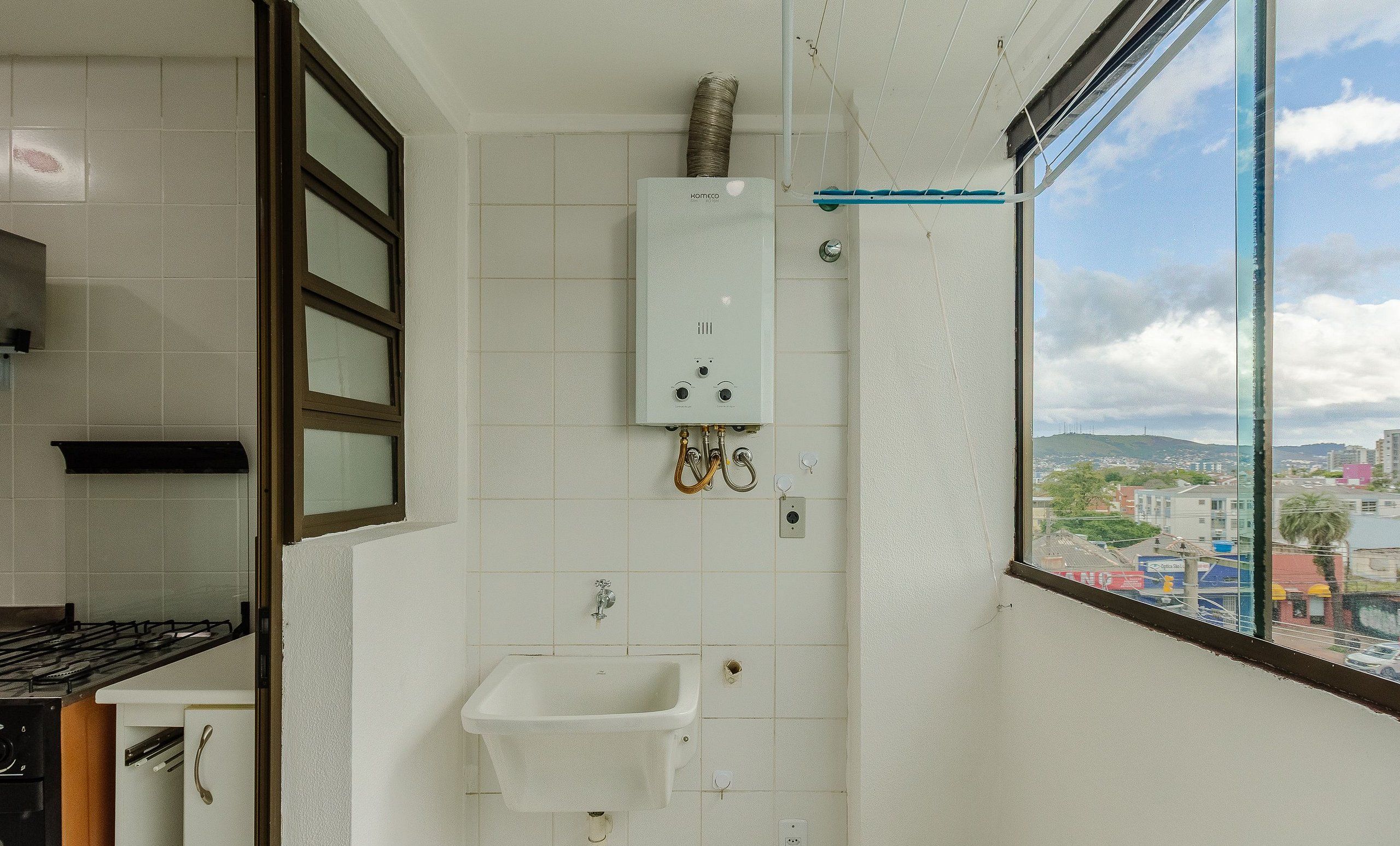 Een badkamer met een raam, een wastafel en een zichtbare boiler.
