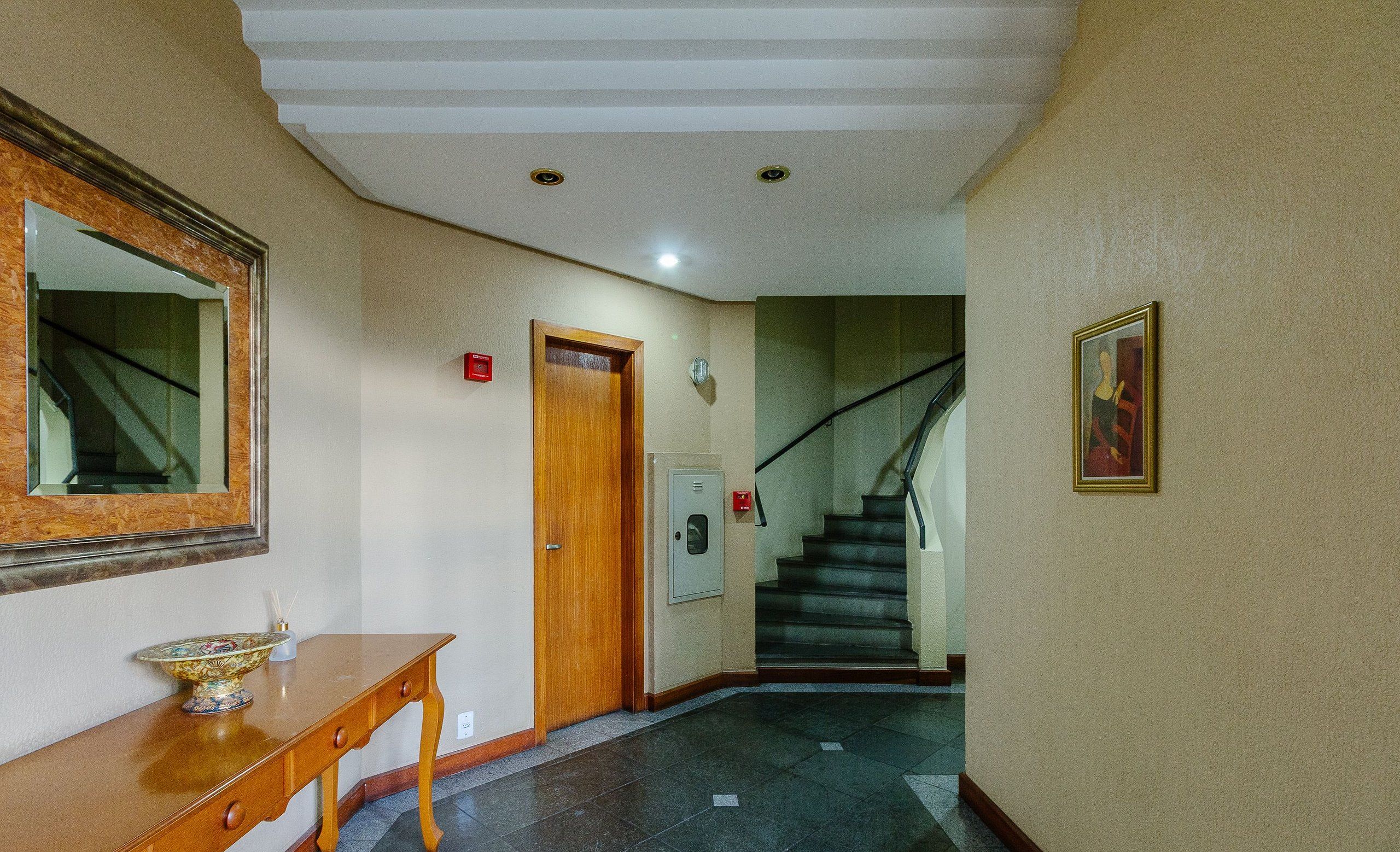 A hallway with a wooden console table, a mirror, a door, and a staircase.