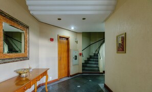 Un pasillo con una consola de madera, un espejo, una puerta y una escalera.