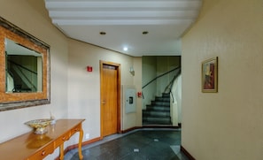 Un pasillo con una consola de madera, un espejo, una puerta y una escalera.