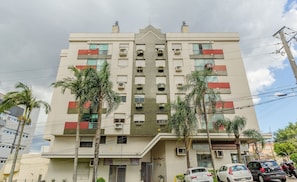 Un edificio de varios pisos con entrada central, unidades de aire acondicionado y un letrero que indica un espacio comercial.