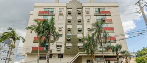 A multi-story building with a central entrance, air conditioning units, and a sign indicating a commercial space.