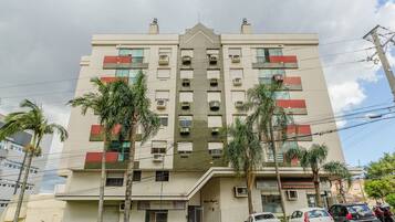 Un edificio de varios pisos con entrada central, unidades de aire acondicionado y un letrero que indica un espacio comercial.