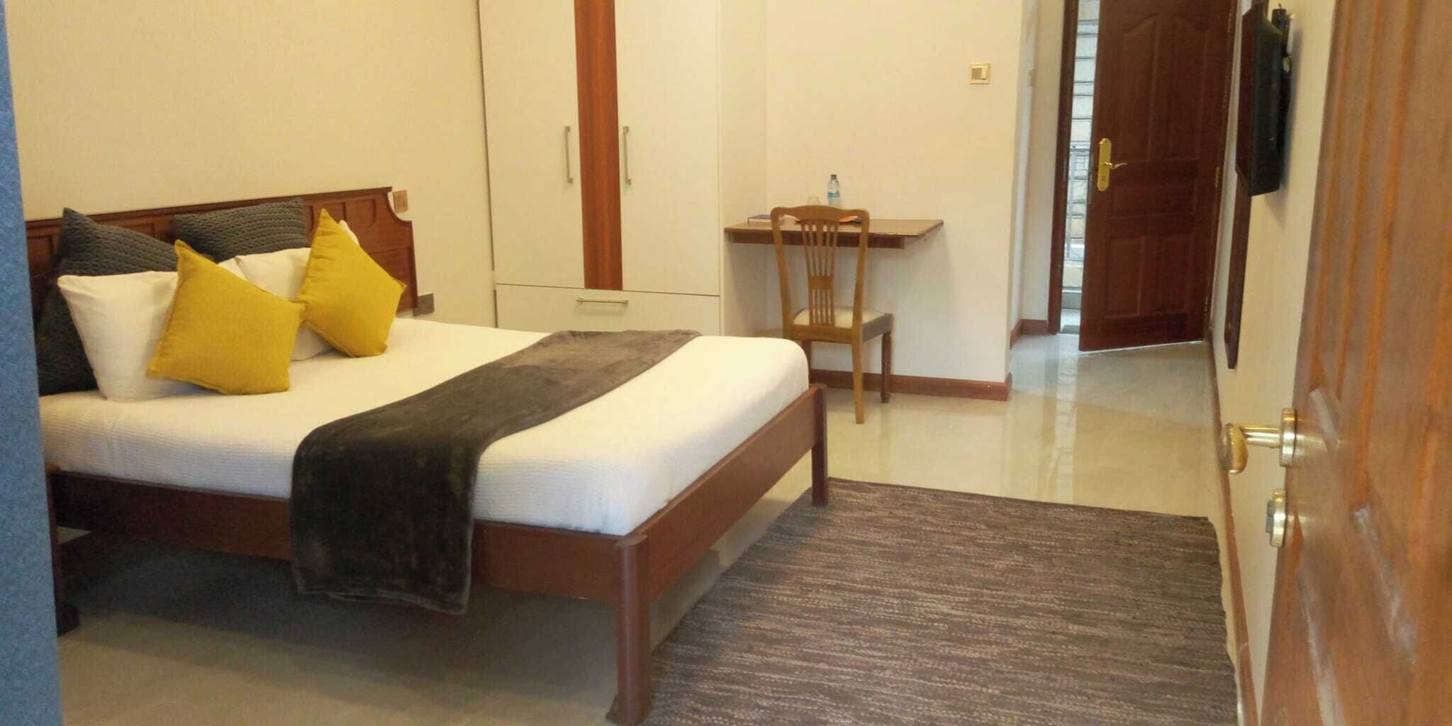 Une chambre d’hôtel avec un lit, une chaise, un bureau et une porte.