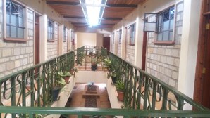 A corridor with a green railing, potted plants, and a central staircase leading to an upper level. - The Exotic House Kericho (Kericho)