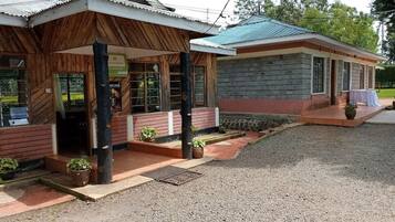 Un edificio con fachada de piedra y revestimiento de madera, que cuenta con un porche con plantas en macetas y una pequeña mesa.