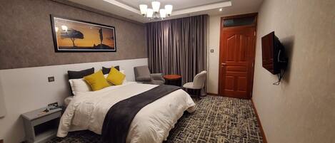 Une chambre d’hôtel avec un lit, un bureau, une chaise, une télévision et une porte.