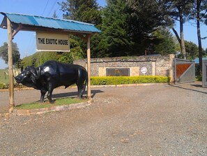 A sign for 'The Exotic House' with a black cow statue in front. - The Exotic House Kericho (Kericho)