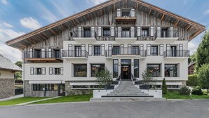 A multi-story building with a modern design, featuring balconies, large windows, and a stone facade. - L'Écrin  (Megève)