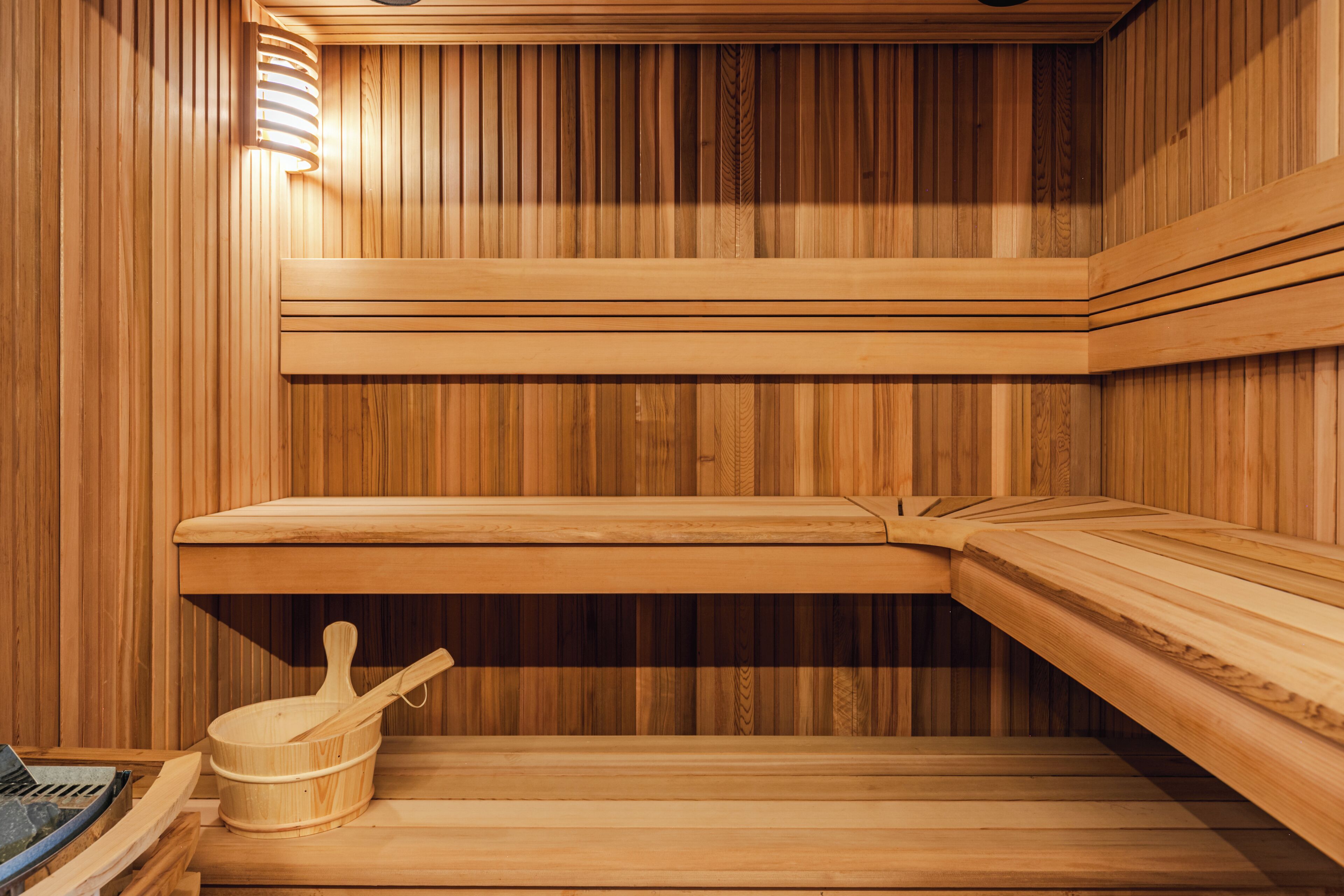 A wooden sauna with benches and a wooden bucket.